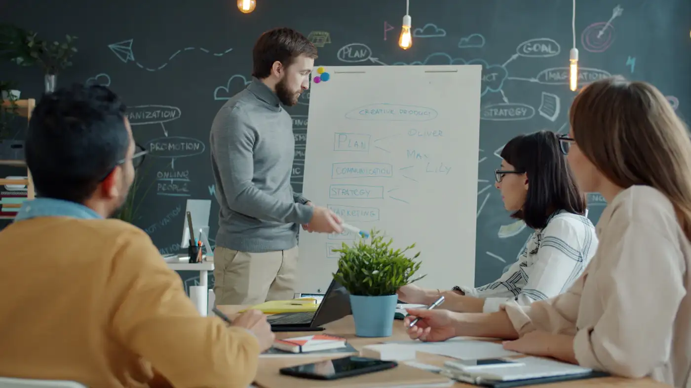 Colleagues working through a problem together at a whiteboard