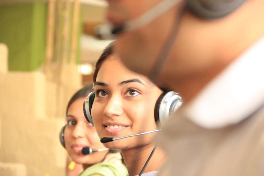 Two support specialists with headsets in a bright office